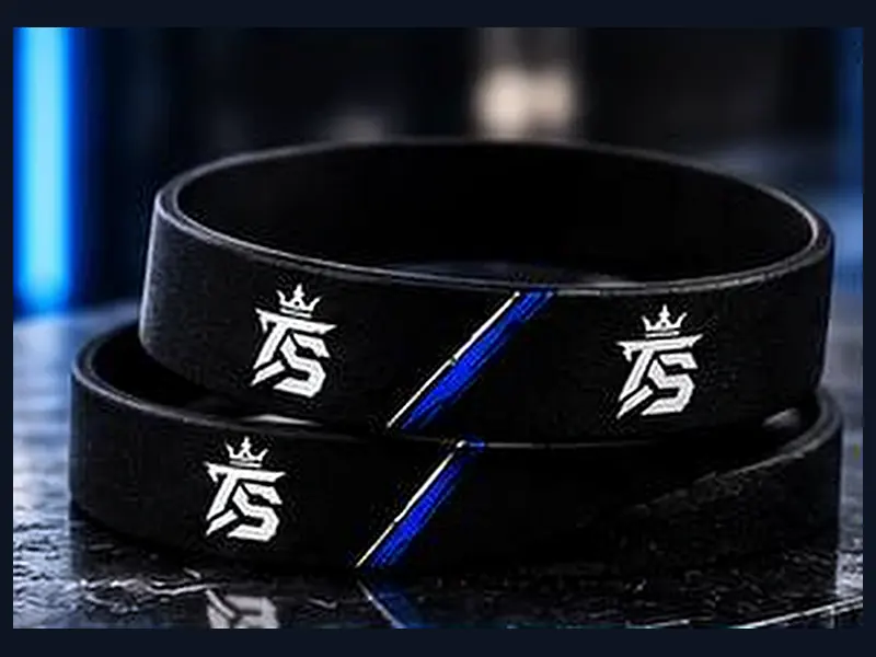 Zwei schwarze Silikon-Armbänder mit TrustAsSports-Logo und blauem Streifen